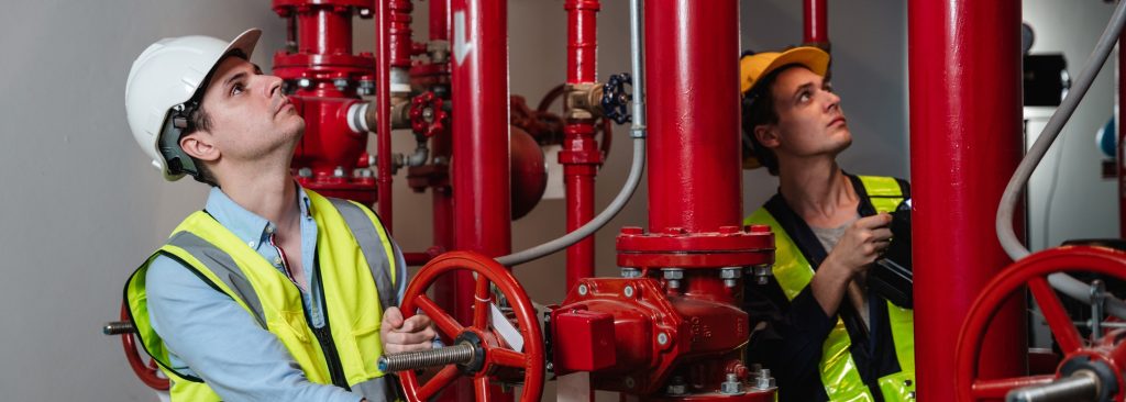 Engineers inspecting the inside plumbing and water valves of an industrial facility.